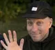 Aleksi wearing a black cap and waving his right hand.